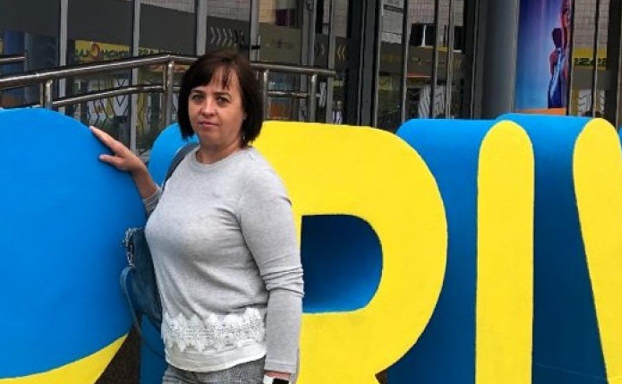 Nina junto al letrero con el nombre y la bandera de su país. 