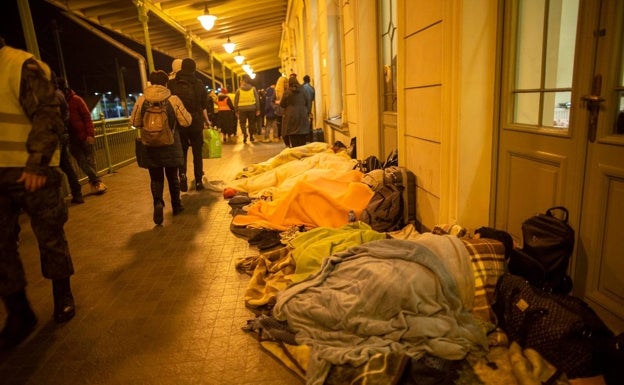 Imagen principal - Refugiados durmiendo en el suelo, Clara Arnal en la estación y familias cruzando la frontera. 