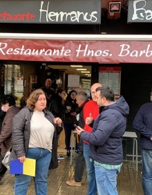 Imagen secundaria 2 - Ucraniano que se va a combatir (posando con una gorra) y compatriotas que esperan la llegada de un familiar; conductores del autobús y puerta del restaurante Hermanos Barberá. 