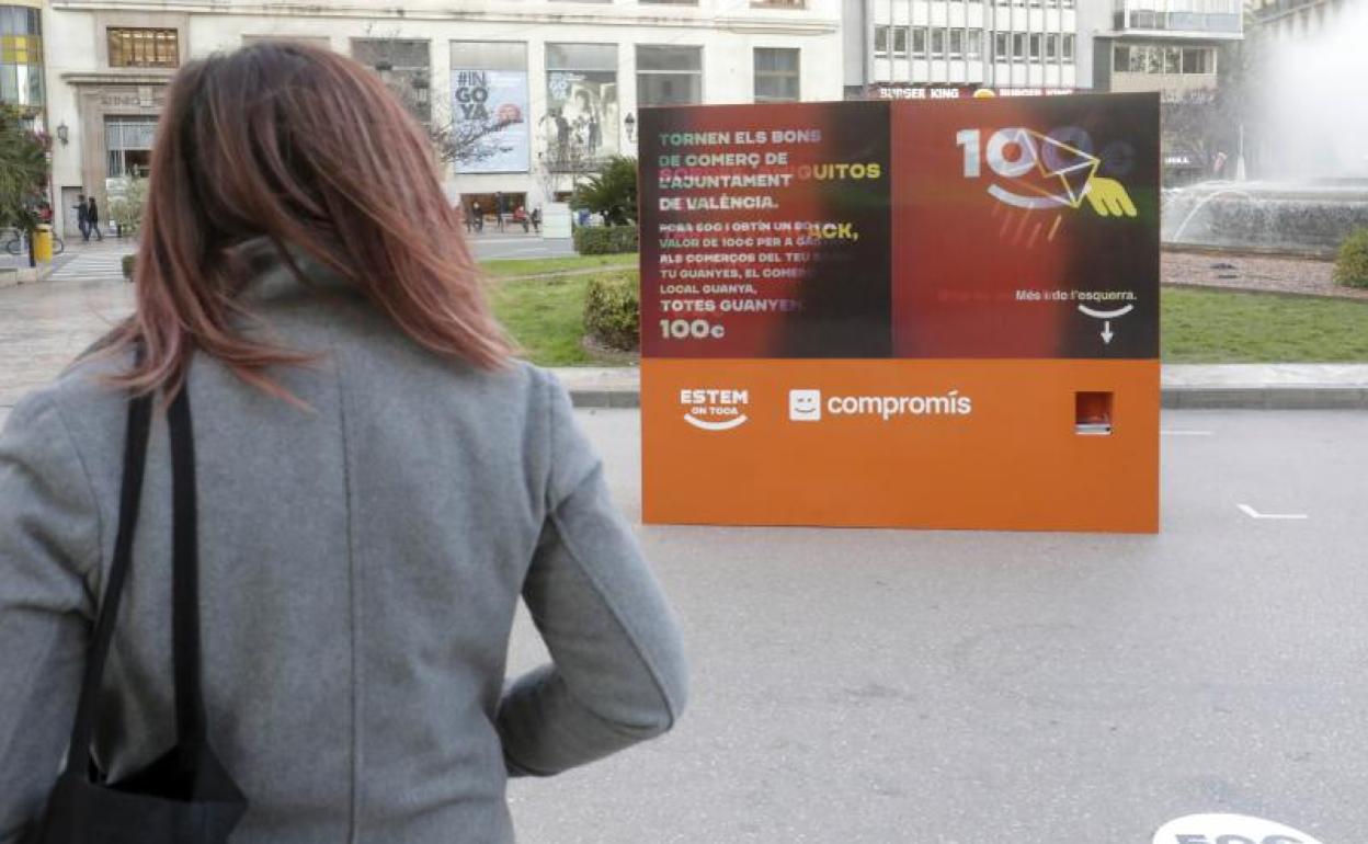 Una mujer observa el cartel de Compromís en la plaza del Ayuntamiento. 