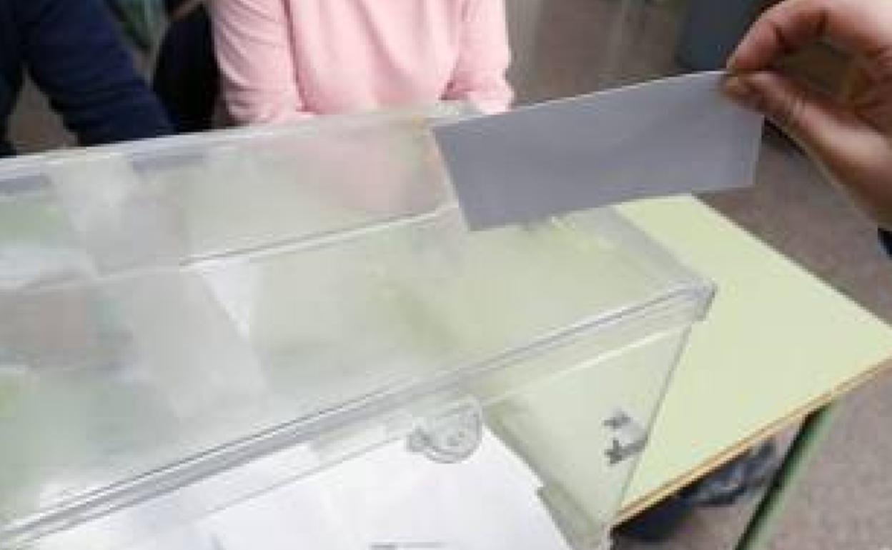 Una persona deposita su voto en la urna. 