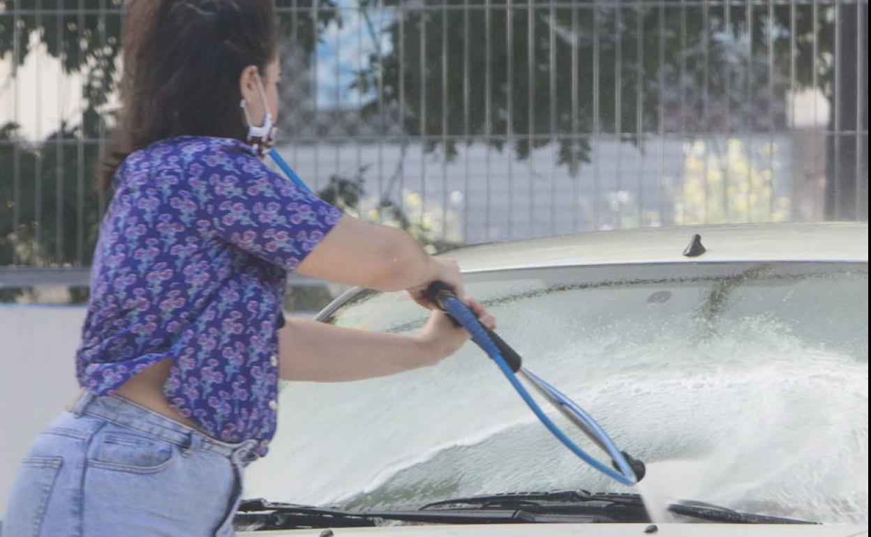 Una mujer lava el coche en un lavadero.