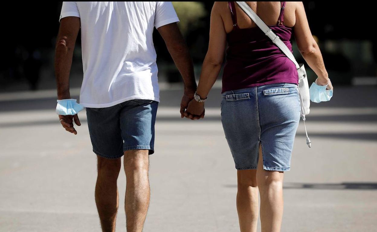 Una pareja pasea por Valencia con la mascarilla quitada. 