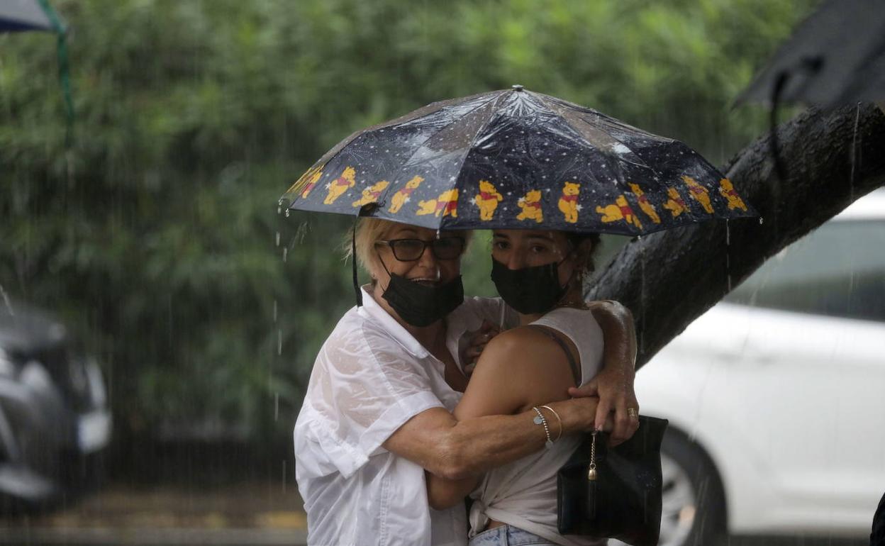 Dos mujeres se resguardan de la lluvia. 