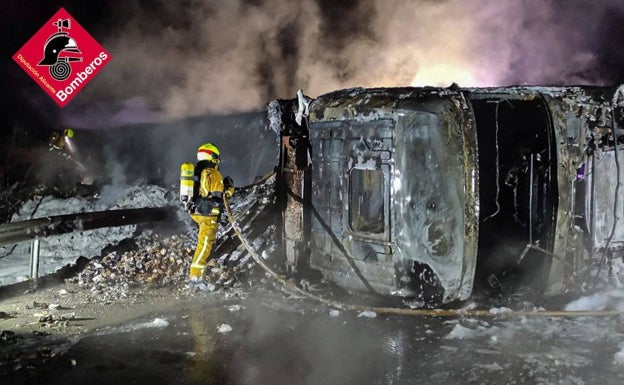 Varios bomberos trabajan en la extinción del camión incendiado. 