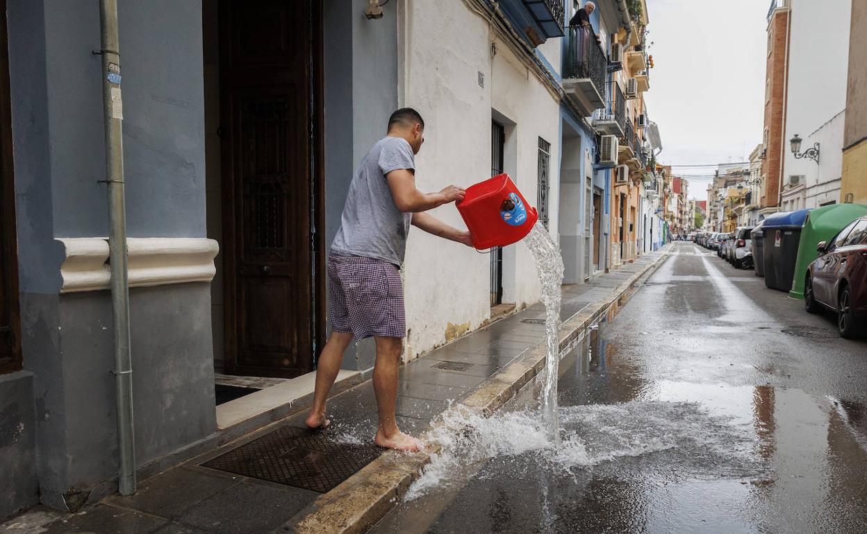 Un vecino saca el agua de su bajo en en el Cabanyal. 