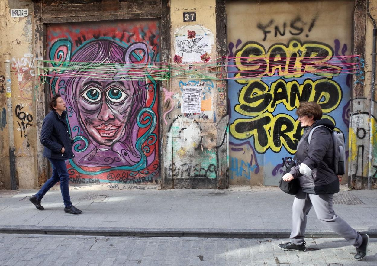 Dos personas caminan frente a grafitis en el barrio del Carmen. txema rodríguez