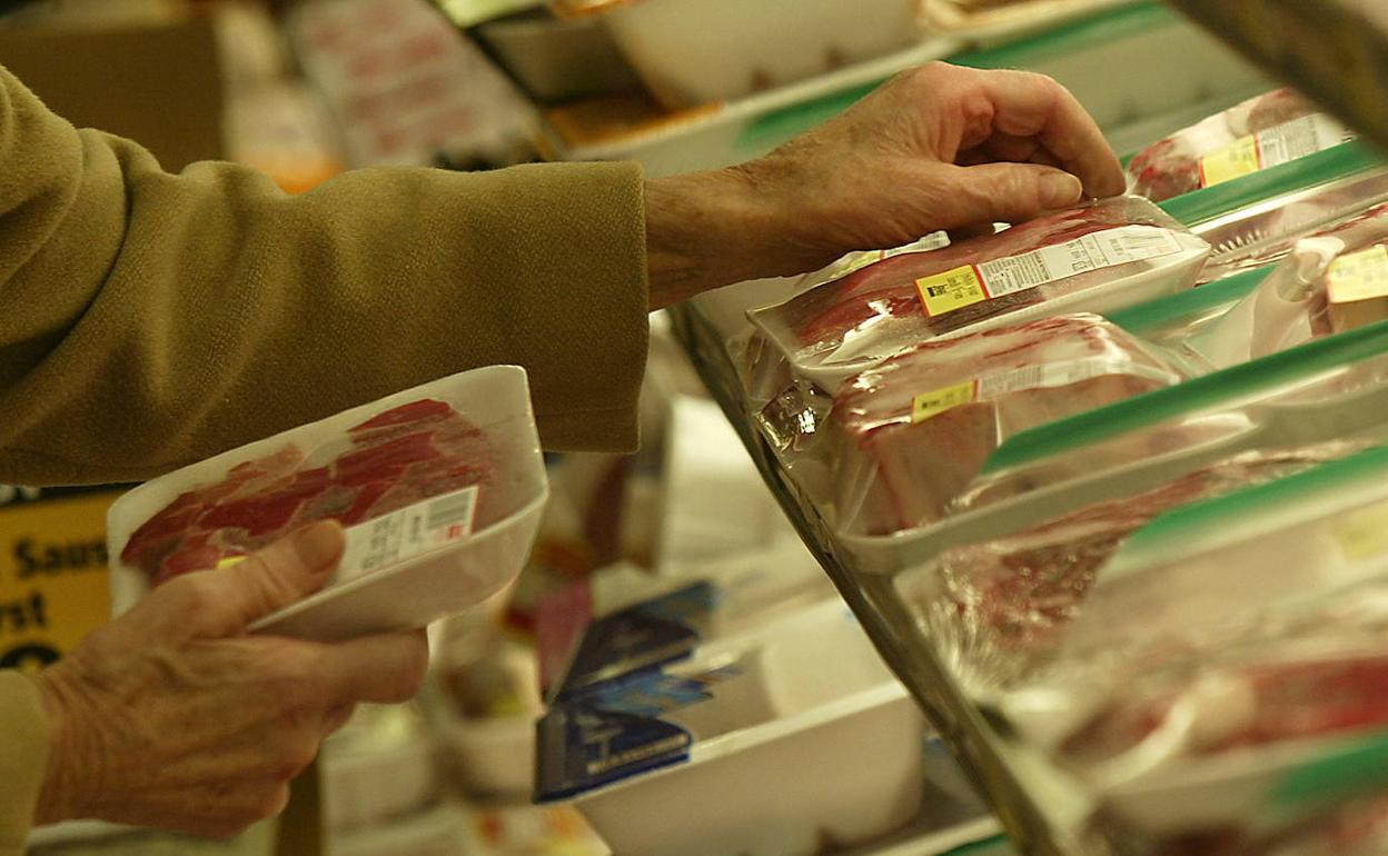 Una mujer pasa ante la sección de carnes envasadas al vacío en un supermercado.