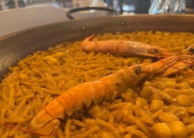 Imagen secundaria 1 - Arriba, fideuà preparada en el Café Bar Diddley de Vilalonga. Abajo el plato típico de Gandia, elaborado en el Hogar del Pescador, en pleno puerto de Gandia. A la derecha los gerentes de Diddley, con una clienta. 