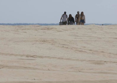 Imagen secundaria 1 - Viositantes de la playa del Cabanyal atravesando la zona de arena y servicio de sombrillas en el local Marina Beach. 