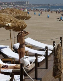 Imagen secundaria 2 - Viositantes de la playa del Cabanyal atravesando la zona de arena y servicio de sombrillas en el local Marina Beach. 