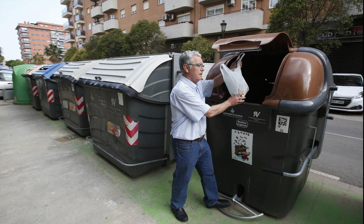 Un vecino deposita la basura en el contenedor marrón en Valencia. 