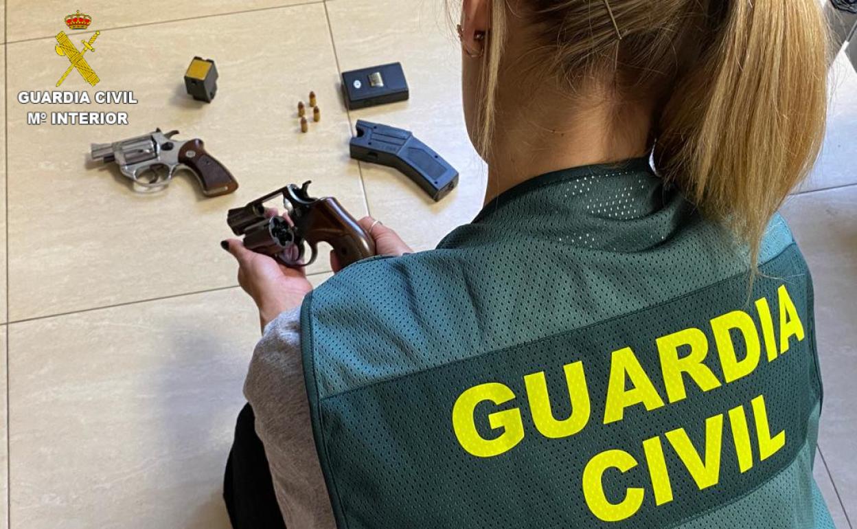 Un agente de la Guardia Civil revisa las armas requisadas. 