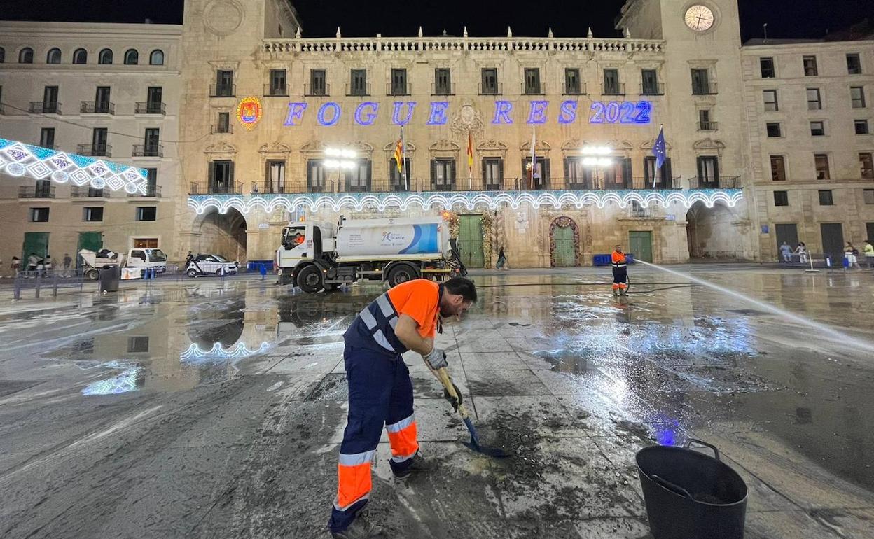 Un trabajador limpia los restos de la cremà de la hoguera oficial en la Plaza del Ayuntamiento. 