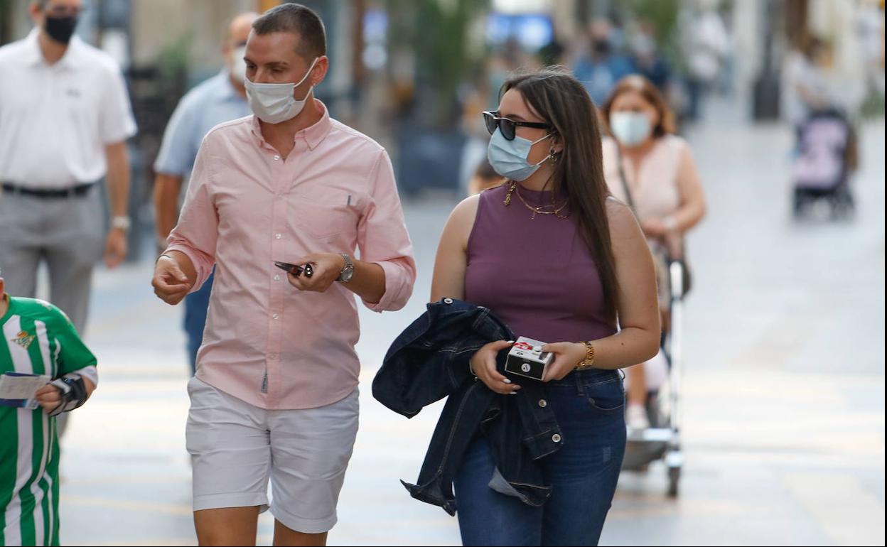 Una pareja pasea con la mascarilla puesta.