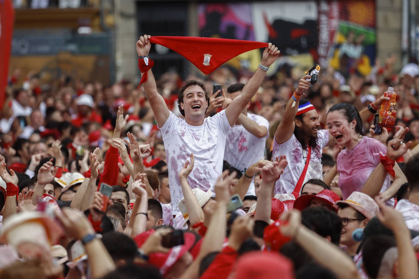 Risas, alegría y fiesta para un grupo de jóvenes que muestran el pañuelico rojo en la Plaza Consistorial de Pamplona antes del chupinazo de los Sanfermines 2022.