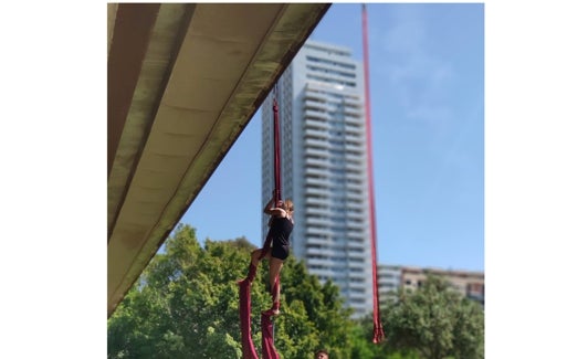 Una joven practica con unas telas en el jardín del Turia, con la Torre de Francia como mudo testigo.