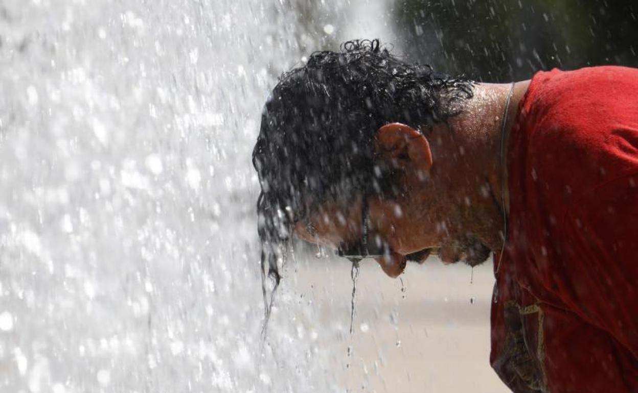 Un hombre se refresca en una fuente de Córdoba. 