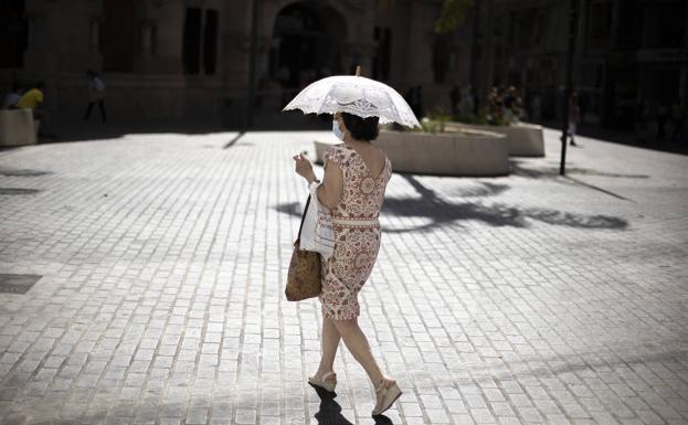 Una mujer se protege del sol con una sombrilla en Valencia. 