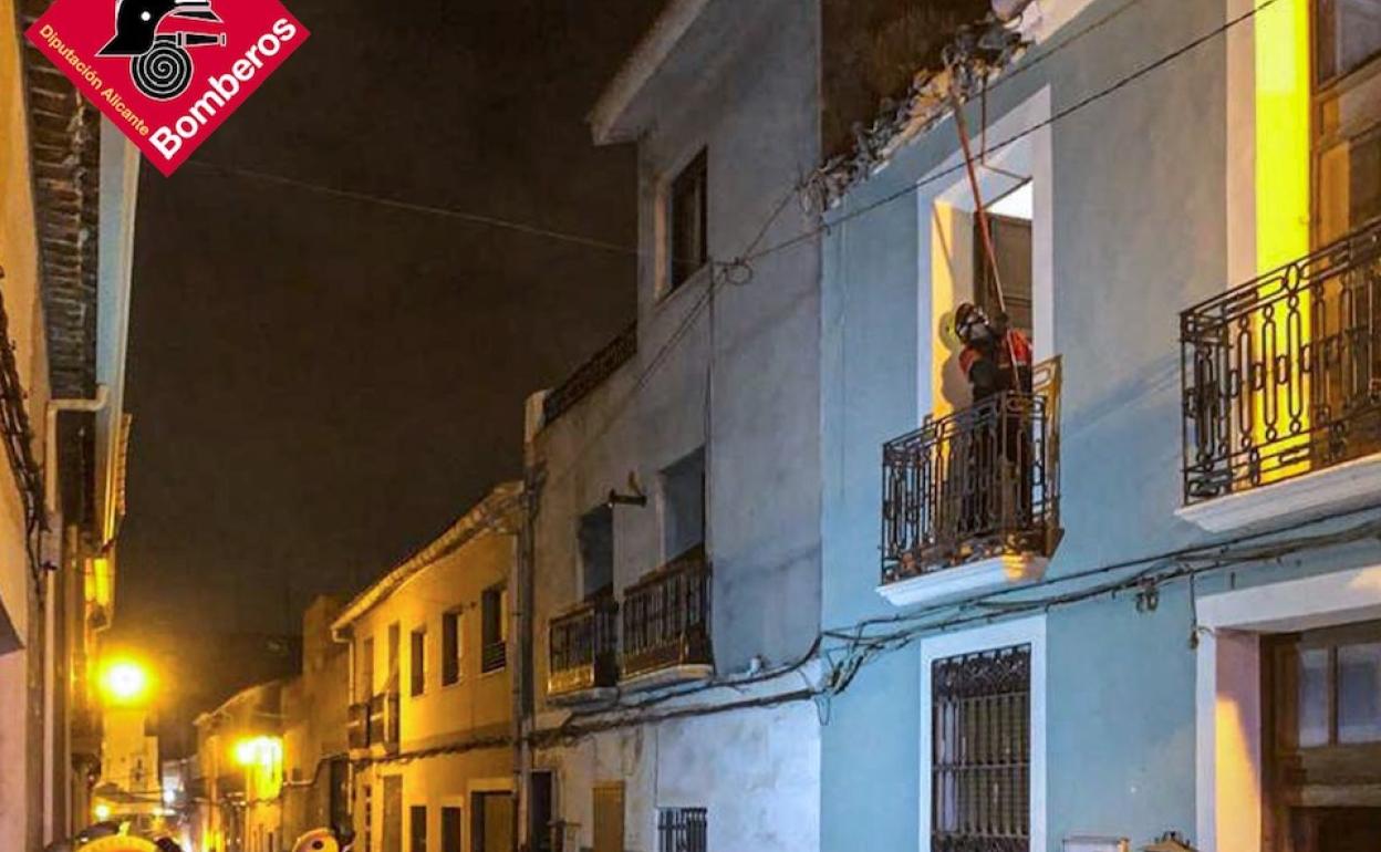 Un bombero retira los escombros que ha dejado la caída del techo de la vivienda. 