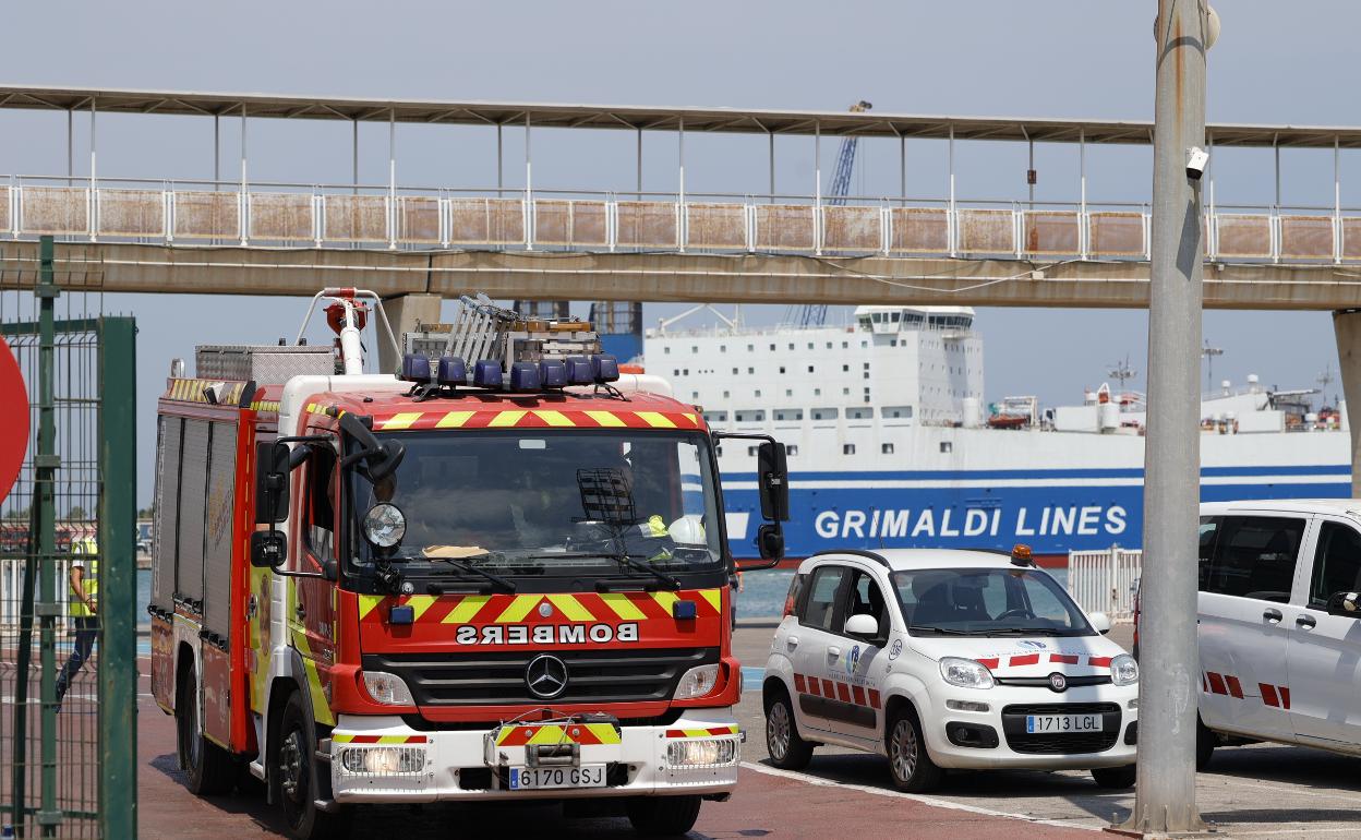 Un camión de bomberos sale del punto donde está atracado el barco que sufrió el incendio, en el muelle de Levante. 