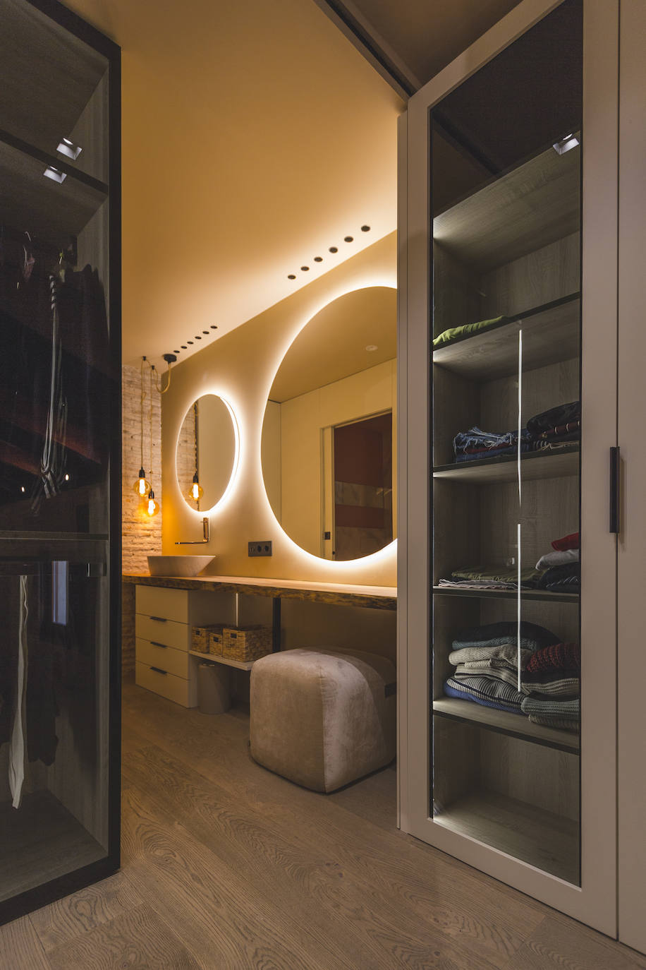 Baño de habitación y vestidor, con lavabo de piedra natural y grifería Lounge de Porcelanosa y puf Season de Viccarbe.