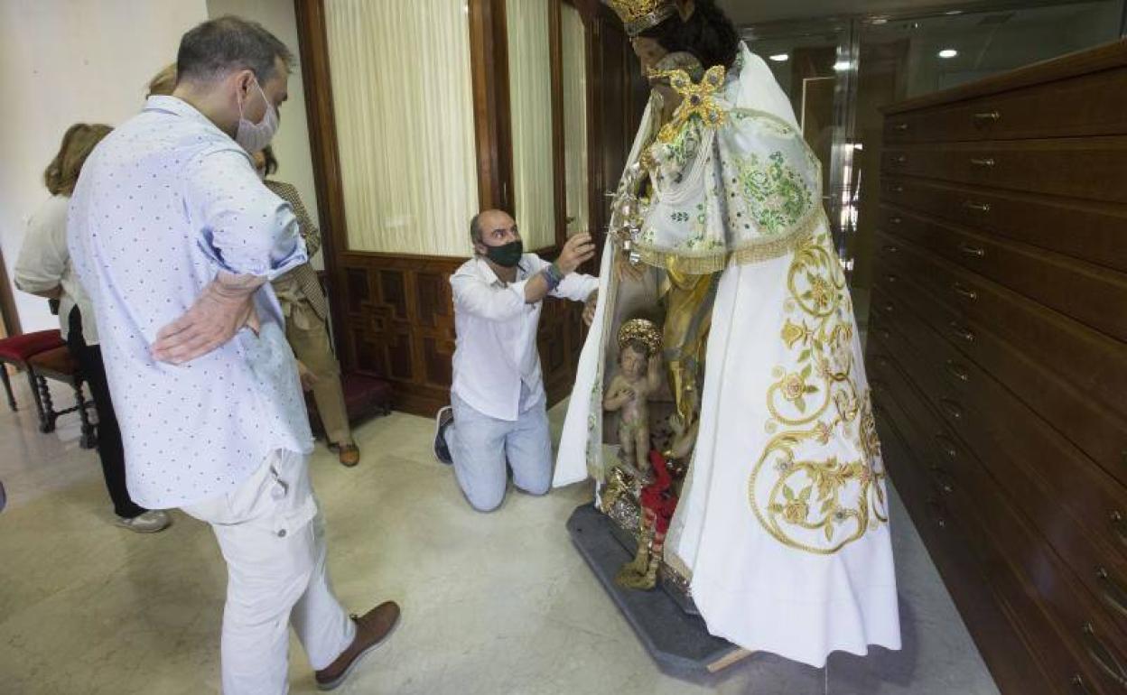 Francisco Perales (arrodillado) coge con alfileres el manto en la prueba que se realizó sobre la Peregrina. 