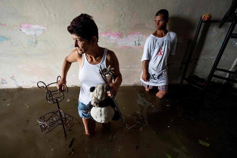 Miembros de una familia tratan de salvar sus objetos personales del agua, en Batabano.