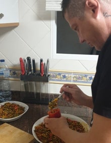 Imagen secundaria 2 - Jordi y Asier, picando los ingredientes para elaborar la 'pebrera', unos pimientos acabados y Jordi introduciendo el relleno. 
