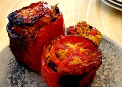 Imagen secundaria 1 - Jordi y Asier, picando los ingredientes para elaborar la 'pebrera', unos pimientos acabados y Jordi introduciendo el relleno. 