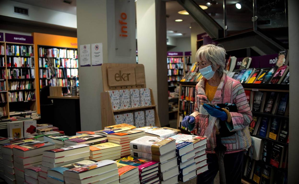 Una mujer ante el expositor de títulos en una librería. 