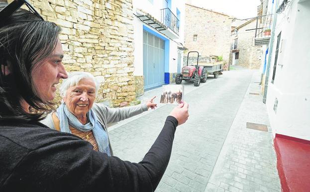 Imagen principal - Participativo en todas las fiestas. Gloria Clemente y Gloria Corell, madre e hija, señalan el punto en que Jaime circuló en un pasacalle en el pueblo. | Vivienda. Un turista pasa frente a la casa que ocupó Jaime y su familia en Pina.