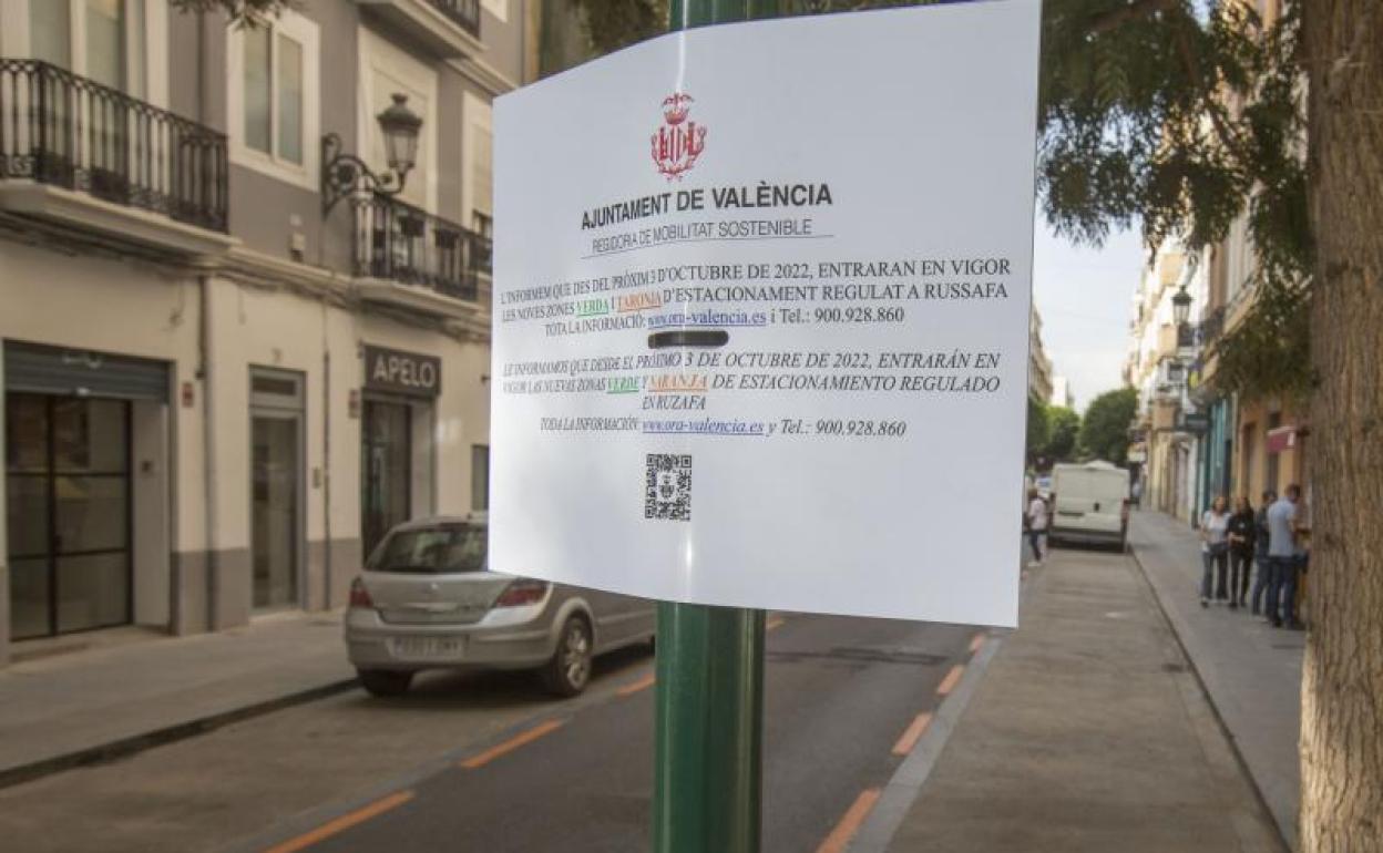 Un cartel informativo, en una calle con zona naranja en el barrio.