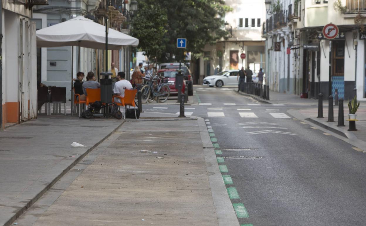 Zona verde de aparcamiento vacía en Ruzafa, con un bar al fondo. 