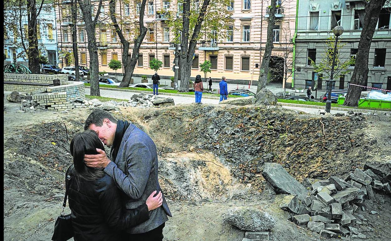 Una pareja se besa ante el cráter provocado por un misil en el parque central de Kiev. 