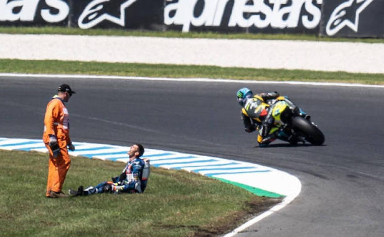 Un comisario atiende a Jorge Navarro junto a la pista donde prosiguió la carrera de Moto2 tras su grave accidente. 