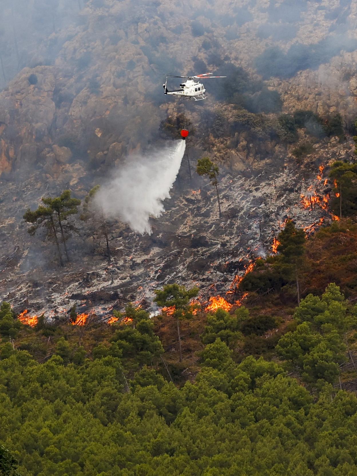 Un helicóptero descarga agua en el incendio de Bejís. 