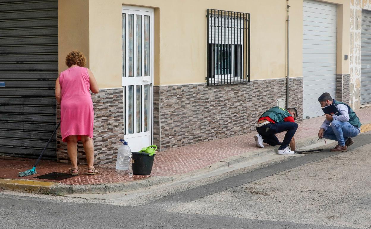 Dos agentes de la Guardia Civil miran por una alcantarilla cercana al domicilio. 