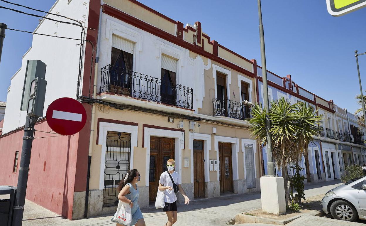 Dos viandantes pasan por una calle del Cabanyal. 