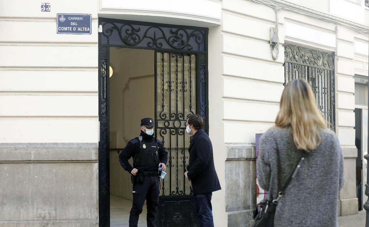 Un policía haba con un hombre en la puerta de la finca donde tuvo lugar el crimen. 