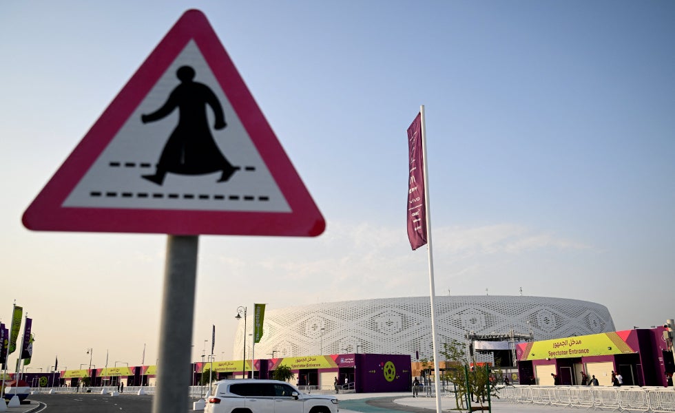 El estadio Al Thumama, tras una señal que marca un paso para peatones en Doha.