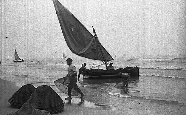 Imagen principal - Imágenes del regreso de los pescadores a la playa del Cabanyal y mujeres y niños observando el pescado. 