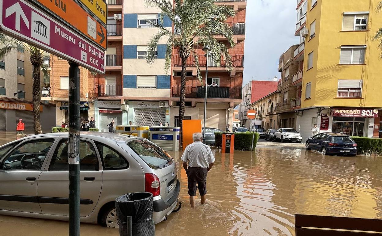 Un hombre cruza la calle anegada por el agua del barranco. 