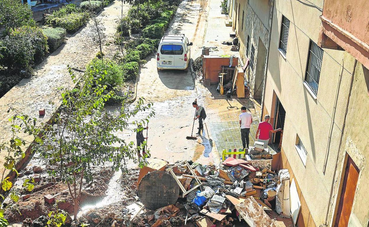 Vecinos de Riba-roja limpian una calle tras el temporal. 