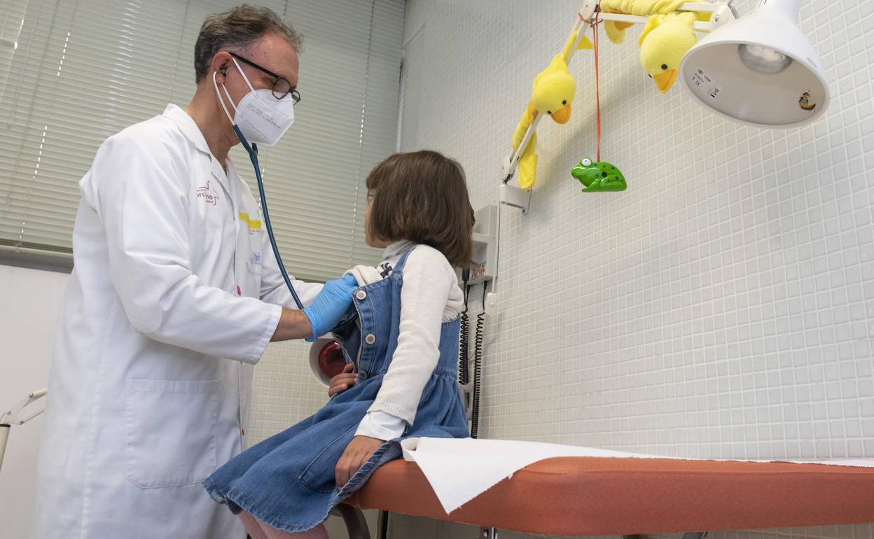 Un pediatra ausculta a una niña en su consulta.