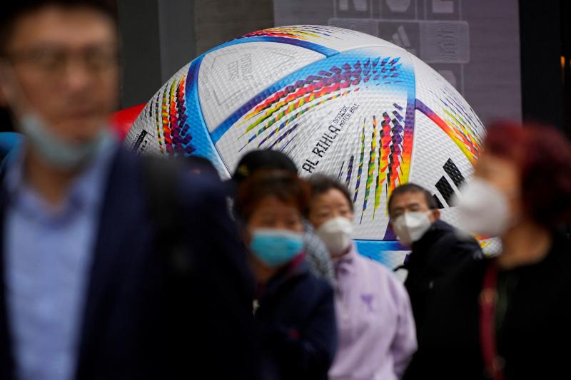 Personas con mascarilla paseando delante del balón oficial del Mundial.