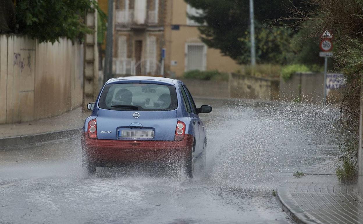 Un coche atraviesa una calle cubierta de agua.