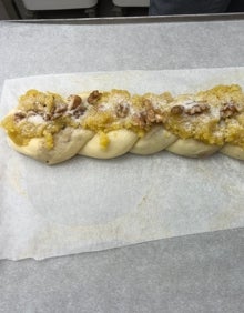 Imagen secundaria 2 - La trenza borgiana en el mostrador de la pastelería Raúl, el pastelero antes de introducir el dulce en el horno y una imagen del postre tras su preparación. 