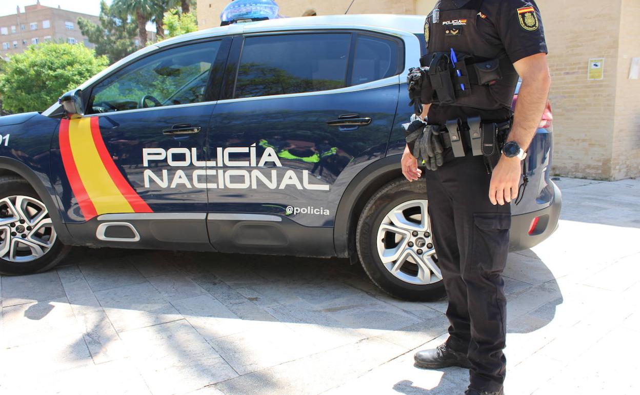 Un agente de la Policía Nacional junto al coche patrulla 