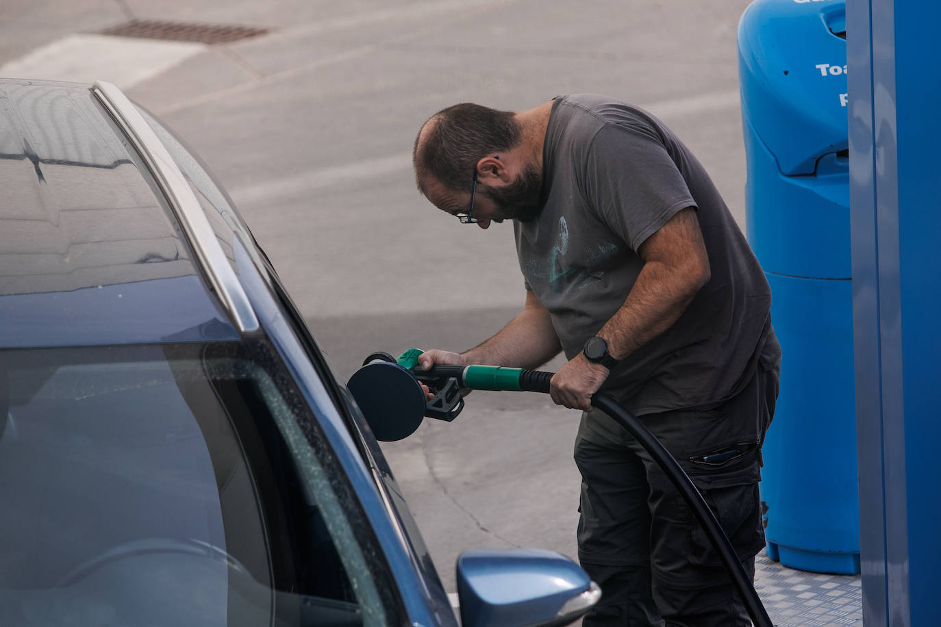 Un hombre reposta su vehículo en una gasolinera. 